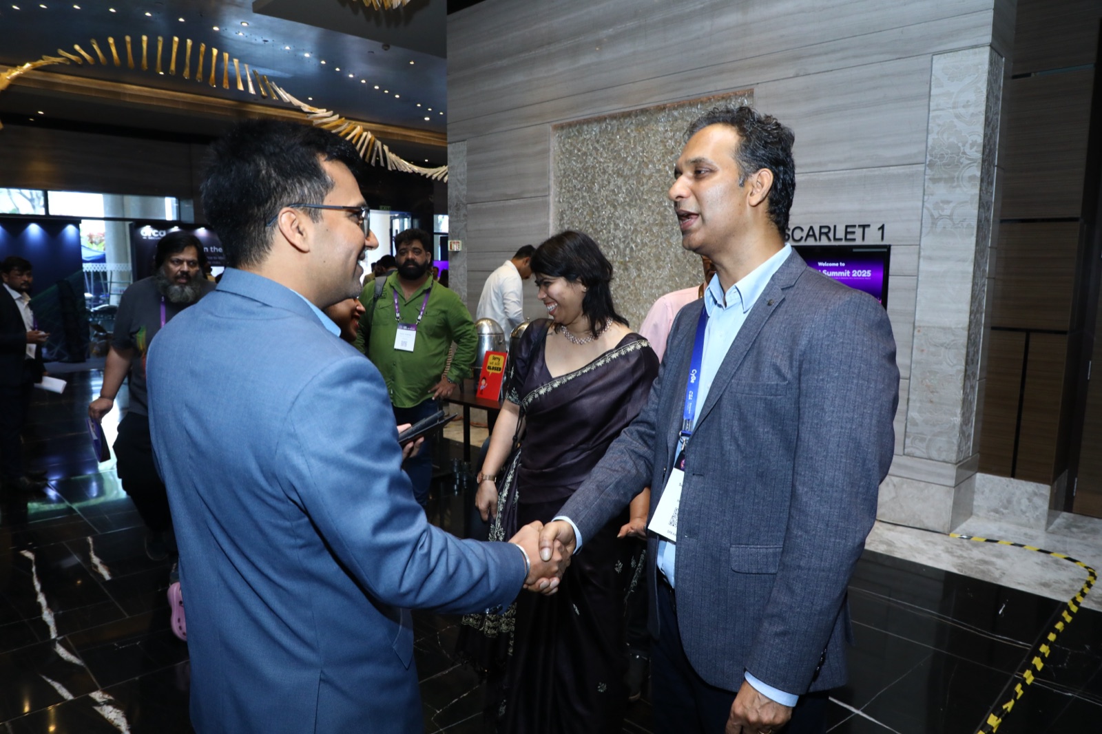 Two attendees shaking hands in the foyer at a CyBe conference